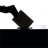 person putting ballot in a box