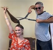 Sarah Van Duyne holding her hair up while someone attempts to cut it with large shears