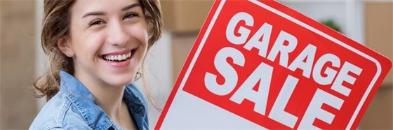 girl smiling holding a garage sale sign