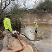 two men using a pump to empty water from a wash