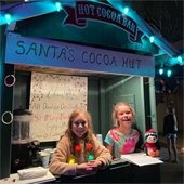 two girls standing in a hut with a "Cocoa hut" sign