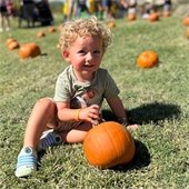 blonde haired boy with pumpkin in grass