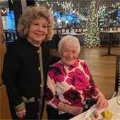 one woman sitting and one standing at a happy hour