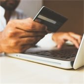 man holding credit card at computer
