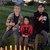 3 boys drinking hot chocolate by a fire