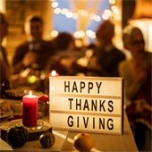happy thanksgiving sign in front of people at a dining table