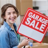 girl in a jean shirt holding a red garage sale sign