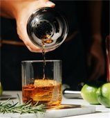 whiskey being poured in glass from shaker