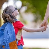 girl with a backpack holding mom's hand